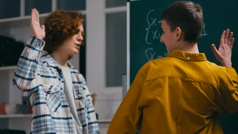 Teen boy helping classmate with math equation near chalkboard, giving high five Stock Footage 251805379