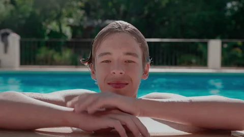 Teen boy inserts aligners at poolside Stock Footage 319876444