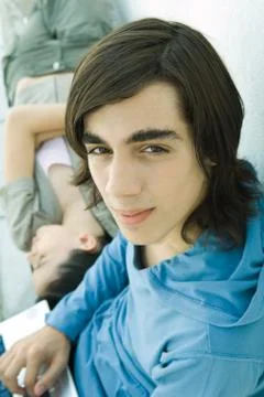 Teen boy looking at camera while female friend lies on back Stock Photos