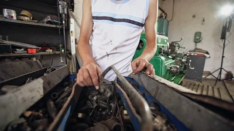 Teen boy looking inside rusty toolbox and searching for detail while working in Stock Footage 97069917