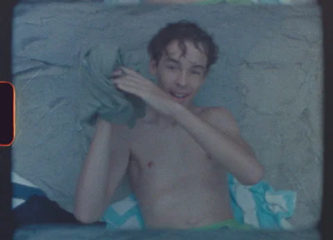 Teen boy playfully throws shirt toward camera Stock Footage 319829173