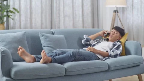 Teen Boy Talking On Smartphone While Lying On Sofa In The Living Room At Home Stock Footage 247981798