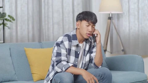 Teen Boy Talking On Smartphone While Sitting On Sofa In The Living Room At Home Stock Footage 247982025