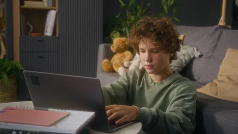 Teen Boy Using Computer Studying and Looking Up at Camera Stock Footage 323359500