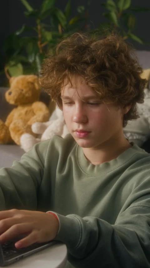 Teen Boy Using Computer Studying and Looking Up at Camera Vertical Stock Footage 323359532