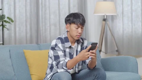 Teen Boy Using Smartphone While Sitting On Sofa In The Living Room At Home Stock Footage 247981899