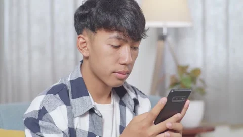 Teen Boy Using Smartphone While Sitting On Sofa In The Living Room At Home Stock Footage 247982666