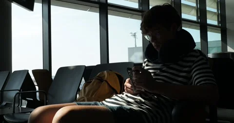 Teen boy using smartphone while waiting at gate Video stock 319872551