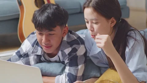 Teen Couple Using A Laptop While Lying On Carpet On The Floor At Home Stock Footage 247974648