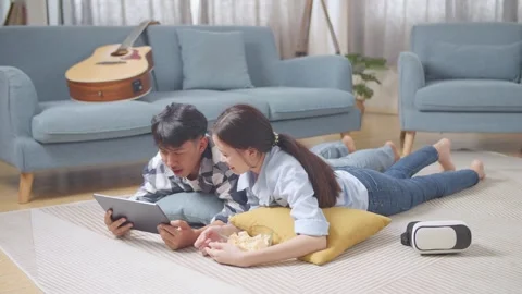 Teen Couple Using Tablet While Lying On Carpet On The Floor At Home Stock Footage 247975657