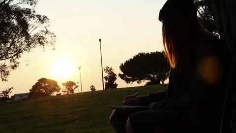 Teen drawing with the sun setting Stock Footage 102026173