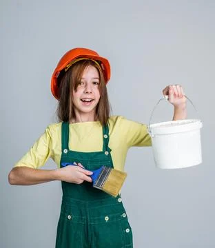 Teen girl laborer in protective helmet and uniform use painting brush and bucket Stock Photos