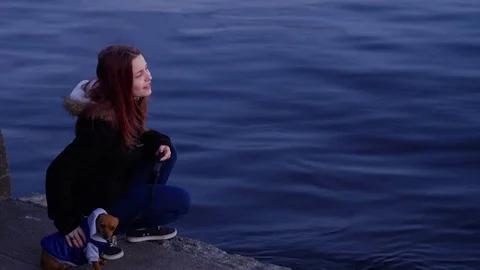 Teen girl with a little dog on a night street near river Stock Footage