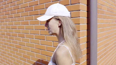 Teen girl wearing cap at brick wall Stock Footage