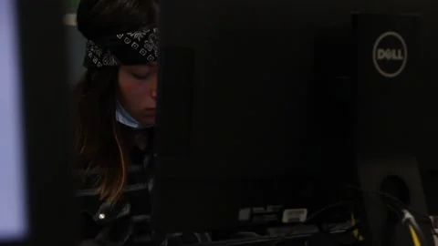 Teen in library, face mask down, wearing bandana, on computer Stock Footage 134675806