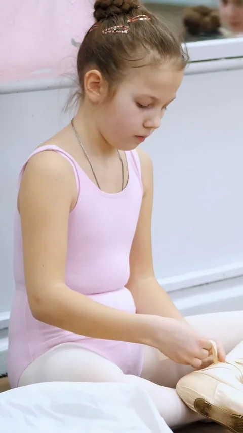 Teen little girl in a pink leotard, prepares for classical ballet dance lesson Stock Footage 313245533