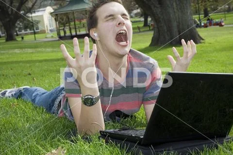 A teen at the park with a laptop having a meltdown. Stock Photos