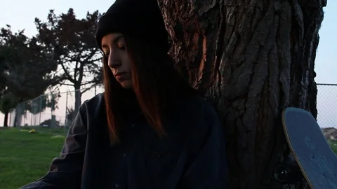 Teen in park by tree, pan down to reveal drawing Stock Footage 101877021