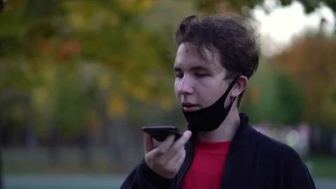 Teen with protective face mask while using smart phone and sending voice message Stock Footage 140670391