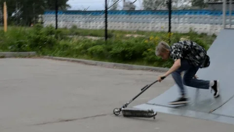 Teen on scooter trying performs a trick in the skatepark 動画素材 133101697