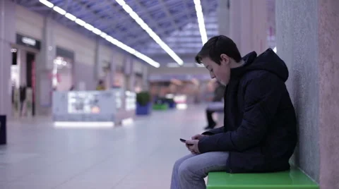 Teen sitting on a bench and playing smartphone Stock Footage 59558945