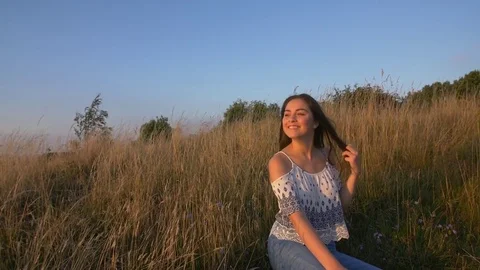 Teen sitting in field at sunset 7 Stock Footage 78060341