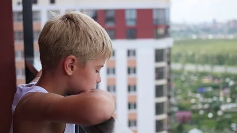 Teen stands on the balcony of a tall building and looks down Stock Footage