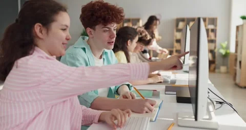 Teen students collaborating at computers in classroom during group study session Stock Footage 333246038