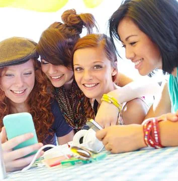Teen technology. A group of adolescent girls laughing as they look at something Stock Photos