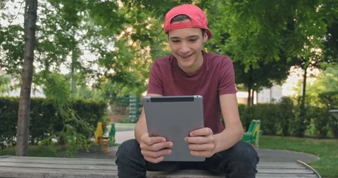 Teen using  tablet in park. Young man using tablet, outdoors. Boy teenager wi Stock-Footage 112337836