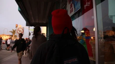 Teen walks down crowded sidewalk in Pismo Beach Stock Footage 80276085