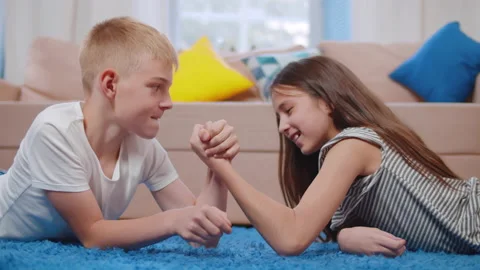 Teenage boy and girl arm wrestle on floo... | Stock Video | Pond5