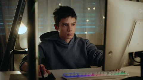 Teenage boy concentrating while using a computer at night in a dark room. Stock Footage 336317030