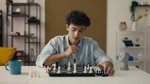 Teenage boy developing a chess strategy, playing a board game alone as a hobby Stock Footage 303170707