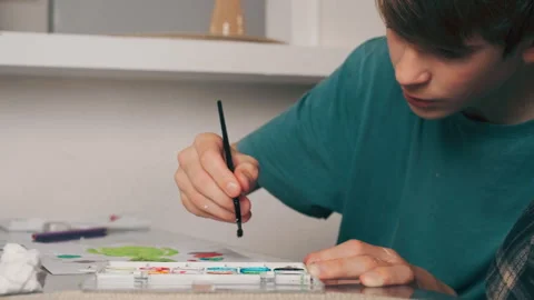 Teenage boy developing creativity and motor skills by painting at home tabl.. Stock Footage 328118274