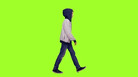 Teenage boy in hoodie walking on green chroma key background Stock Footage