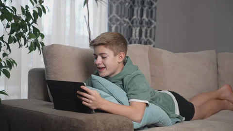 Teenage Boy lying on sofa using tablet. Scrolling social media, Stock-Footage 270362598