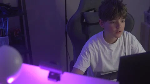 Teenage boy playing computer game in dark room with flashing light, child's Stock Footage 304867206