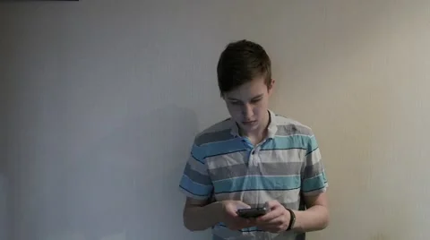 Teenage boy  sms texting using app on smart phone at night near the wall Stock Footage 63323802