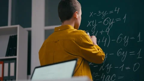 Teenage boy solving math equation near chalkboard, puzzled with a problem Stock Footage 251805470