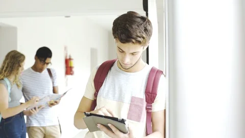 Teenage boy using a digital tablet in college corridor Stock Footage 106268355