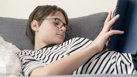 Teenage boy using digital tablet computer at home couch at home. Child looking Stock Footage 221193176