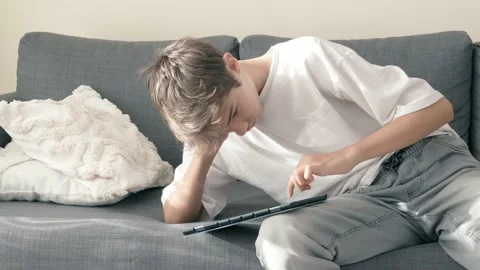 Teenage boy using digital tablet computer at home couch. Child looking at gadget Stock Footage 221362244