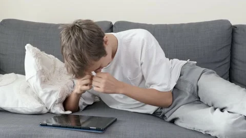 Teenage boy using digital tablet computer lying on couch at home. Happy kid Stock Footage 221708815