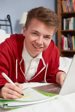 Teenage Boy Using Laptop For Homework In Bedroom Stock Photos