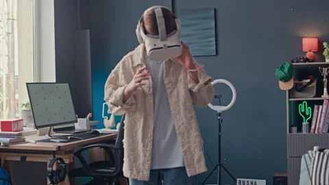 Teenage Boy Using Laptop while Young Girl Examining VR Headset at Home Stock Footage 319738424