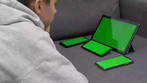 Teenage boy using multiple electronic internet devices in same time. Kid Video stock 169963783