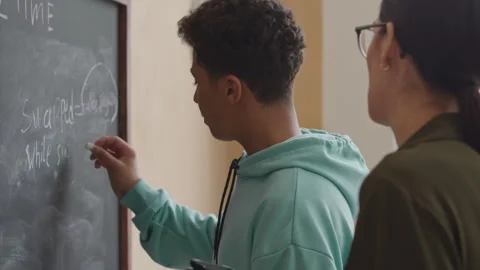 Teenage Boy Writing Programming Formula on Blackboard in Class Stock Footage 248531636