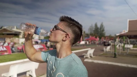 Teen boy drinking water outdoors Stock Video Footage by ©VaLiza #199836514