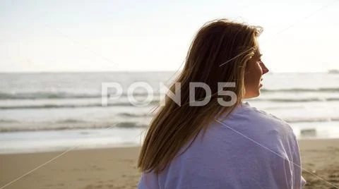 Teenage caucasian girl with brown hair looking at the Pacific Ocean from behind. Stock-Fotos